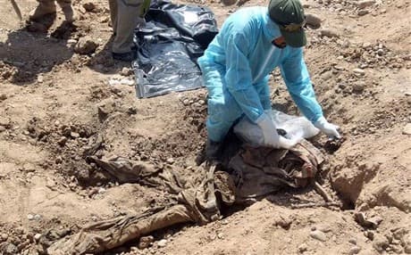 A member of the Iraqi security forces inspects a mass grave. Photo : AFP