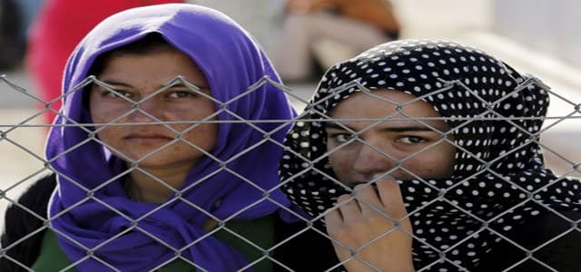 Yazidi refugees stand behind fences in the southern Turkish town of Midyat. Photo: Reuters