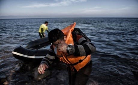 A man hides his face as refugees and migrants arrive on the Greek island of Lesbos after crossing the Aegean Sea from Turkey on November 11, 2015. Photo: AFP.