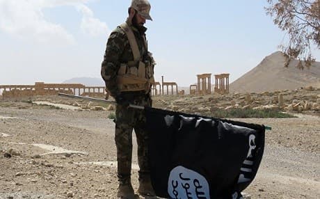 A Syrian soldier holds the ISIS flag near the ancient site of Palmyra after its recapture from by the army. AFP photo