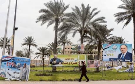 An Iraqi man walks past provincial election posters in Baghdad. Photo: AFP