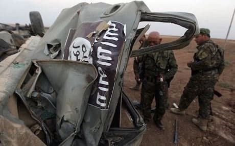 Kurdish Peshmerga fighters inspect an ISIS vehicle destroyed by a US airstrike. Photo: AFP