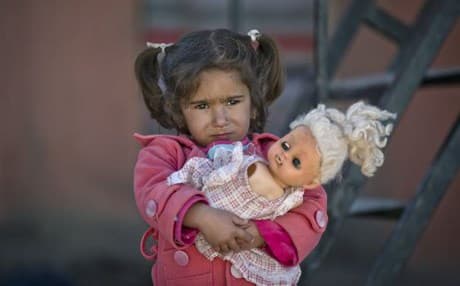 A girl holds a doll as refugees wait for the funeral convoy of 19 year-old Syrian Kurdish fighter. AP photo
