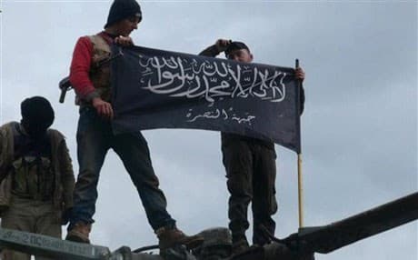 Rebels from al-Qaida-affiliated Jabhat al-Nusra, also known as the Nusra Front, wave their brigade flag, as they step on the top of a Syrian air force helicopter at Taftanaz air base. AP file photo