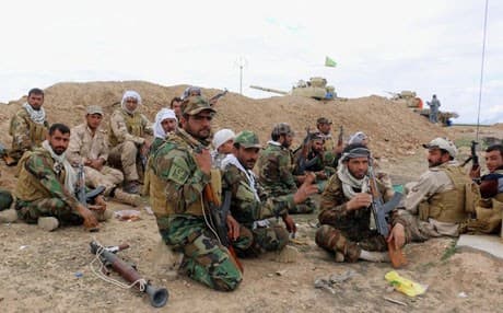 Shiite militiamen rest behind a sand berm as the Iraqi army, supported by volunteers, battles Islamic State extremists outside Tikrit. AP file photo.