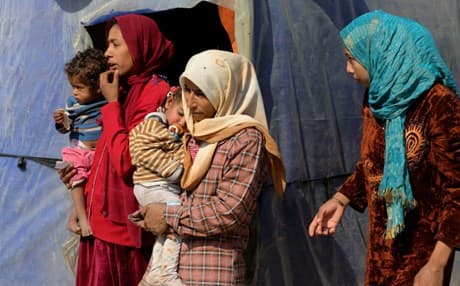An Iraqi woman, who fled her town after the advance of Islamic militants, holds a child at a camp for displaced Iraqis outside Baghdad, Iraq. AP Photo.