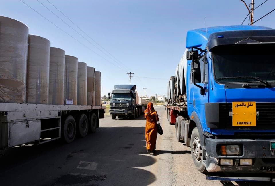 In this picture taken on Sunday, April 26, 2015, a woman walks through lines of trailer trucks sitting idle at the Jaber border crossing between Jordan and Syria north of Mafraq. AP file photo. 