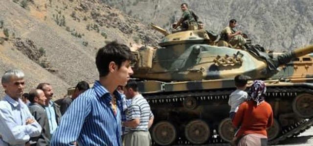 Residents stand near Turkish armored vehicles outside a military outpost. AP photo. 