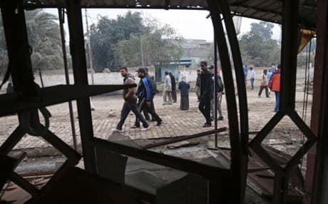 This AP file photo shows civilians walk past the aftermath of a car bomb explosion in Baghdad