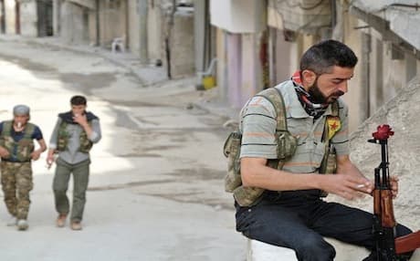 A member of the Kurdish People's Defense Units (YPG) displays a flower on his AK-47 rifle as he holds a position in the city of Aleppo. Photo: AFP