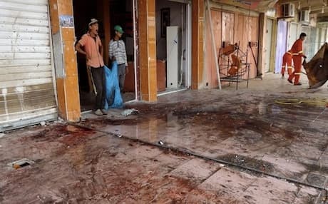 Workers clean the site of a suicide bombing that ripped through a crowded cafe in the northern city of Kirkuk on July 13, 2013. Phot: AFP