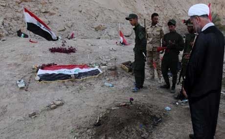 Iraqi Shiite fighters, pray at a burial site believed to hold victims of a June massacre. AFP file Photo.