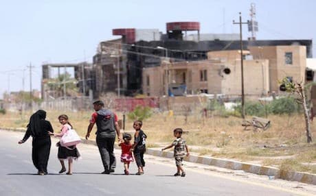 In this Sunday, June 21, 2015 photo, a displaced family walks towards their home in Tikrit, 80 miles (130 kilometers) north of Baghdad, Iraq. Civilians are trickling back into Saddam Hussein’s hometown as they look to start anew, the consequences of a year under Islamic State rule conspicuously written on its charred buildings and damaged homes — AP File Photo.