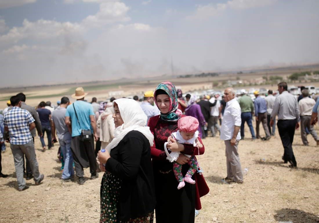 People standing on the Turkish side of the border with Syria, on the outskirts of Suruc, Turkey, watch as smoke rises over Kobani, in Syria, June 27, 2015. Photo: AP. 