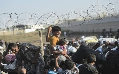 Syrians fleeing the war pass through a broken down border fence to enter Turkish territory illegally near the Akcakale border crossing last month.  AFP photo.
