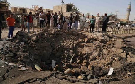 Civilians inspect a crater caused by a suicide car bombing at a busy market in Khan Bani Saad in the Diyala . Photo: AP