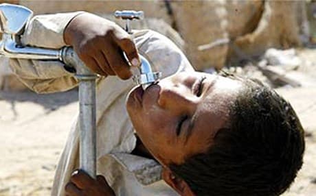 An Iraqi boy drinks from a tap at a camp for displaced people in Najaf. AFP file photo
