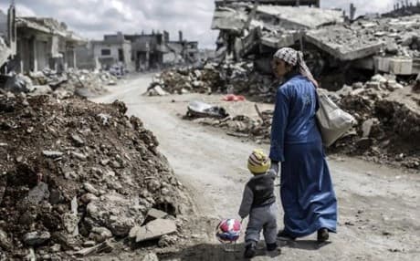 A Kurdish Syrian woman walks with her child past the ruins of Kobani after ISIS had been pushed out of the town earlier this year. AP photo