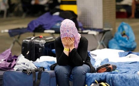 A woman covers her face as she sits on her bed at a registration point for refugees and migrants in Neu Isenburg, Germany, Friday, Sept. 11, 2015. (AP Photo/Michael Probst)