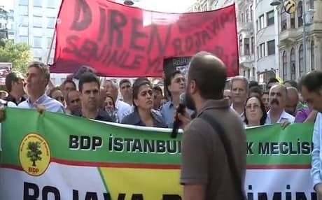 Protesters holding signs and listening to speeches in support of the Syrian-Kurdish plight.