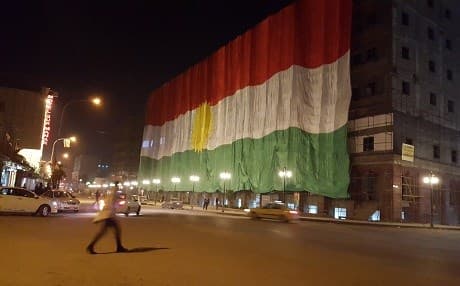 A large Kurdish flag hanging on the side of an unfinished market building in downtown Erbil on the Kurdish national flag day, December 17, 2015. Photo by Ayub Nuri