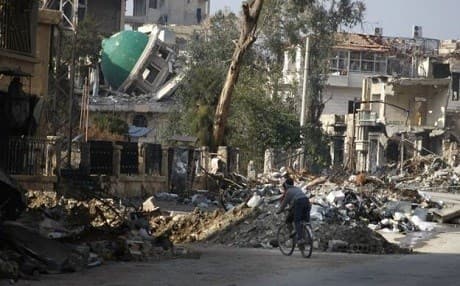 Two Deir al-Zour children riding a bicycle through the rubble. Photo: AFP