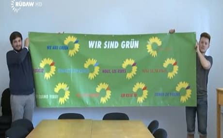 Picture of two young men holding the Green Party sign, the party which Berivan Aymaz, the first Kurdish candidate in the German Parliamentary Elections, is running under. 