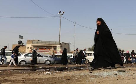 A woman walks past a pool of blood on the aftermath of a suicide bomb attack in the Shiite-majority district of Kadhimiyah, Baghdad. AFP File Photo. 
