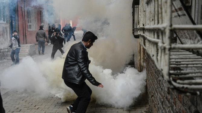 A man tries to avoid the smoke of a gas canister fired by the police in the Sur district of Diyarbakir. Jan, 2016. AFP