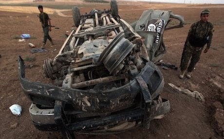 Peshmerga forces inspect an ISIS vehicle destroyed in an airstrike. Photo: AFP