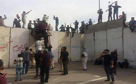 Sadr supporters climb onto blast walls surrounding Baghdad’s Green Zone on Saturday. Photo: AP