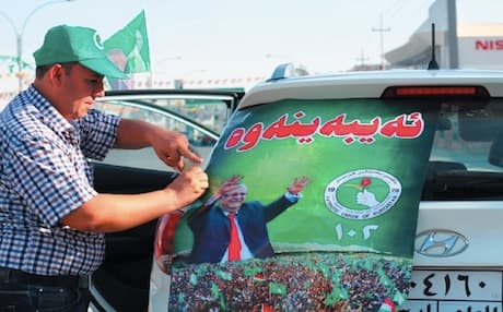A PUK election campaigner fixing a poster on the back of a car that reads, "We will win". Photo: Rudaw