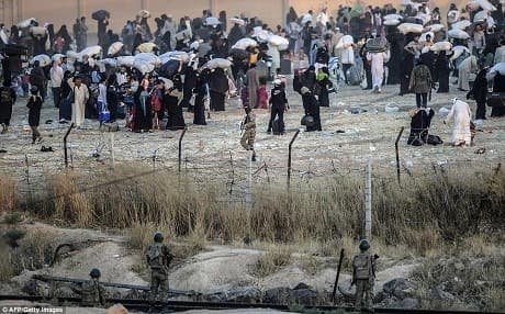 Turkish border guards watch ISIS militants in Syria order refugees away from the Tal Abyad-Akçakale border crossing in June 2015. Photo: AFP
