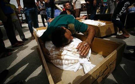 Iraqi men mourn over bodies after they lost five members of their family in a suicide bombing in Karrada, Baghdad. AFP photo.