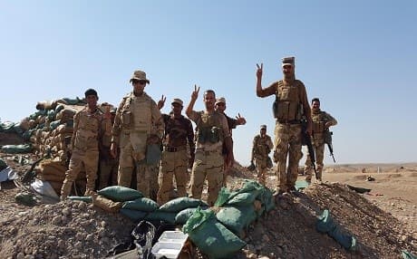 Iraqi soldiers wave the victory sign on top of a hill outside the village of Nasr on June 14 in their drive towards Gayara. Photo by Ayub Nuri