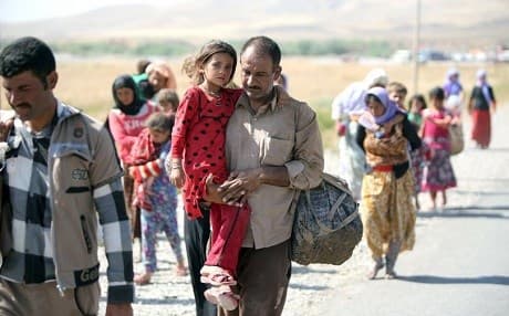 A Yazidi man carries his daughter across the Iraq-Syria border at Fishkhabur after fleeing the Islamic State on August 11, 2014. Photo: Ahmad al-Rubaye/AFP