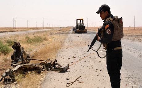 A member of Iraqi government forces inspects a wreckage on the side of a road to Qayara Air Base. AFP file photo