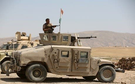 A Kurdish Peshmerga fighter sits atop an armed military vehicle in Bashiqa. AFP file photo.