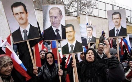 Syrians hold up banners of Russian President Vladimir Putin and his Syrian counterpart President Bashar al-Assad. AP file photo. 