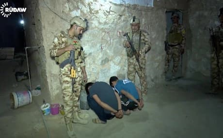 A Peshmerga soldier looks over two ISIS suspects captured recently in Kirkuk. 