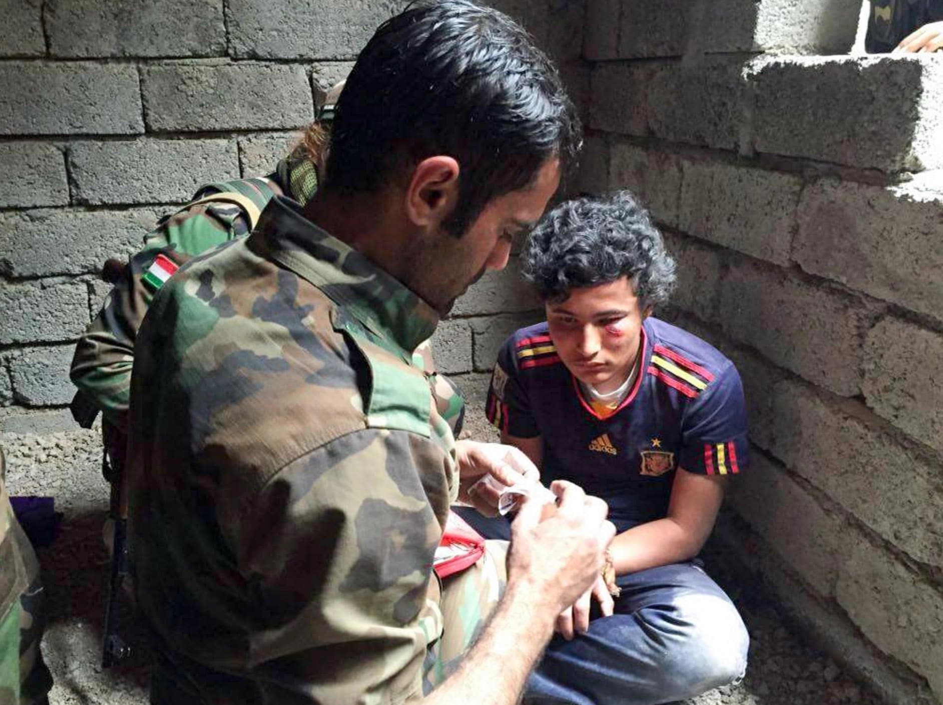 Peshmerga soldiers treating the wounds of Hassan Hamza, 21, an ISIS executioner captured in battle on the Narawan front near Mosul, October, 2016. Photo: Rudaw.  