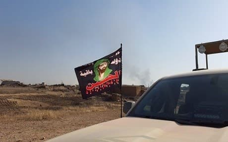 A flag of the Shiite imam Hussein waving on an Iraqi army vehicle in Nasr village near Qayyarah, south of Mosul. Photo by Ayub Nuri
