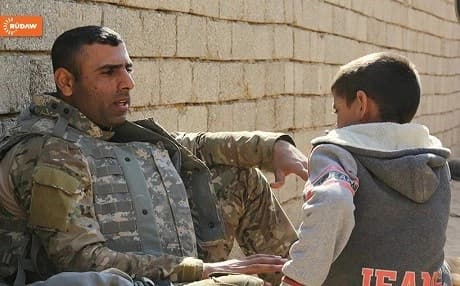 Member of Iraqi security forces chats with a child in Mosul. Photo:Rudaw