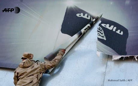 A member of the Iraqi security forces tears down an ISIS poster in east Mosul after its liberation. Photo: Mahmud Salih/AFP