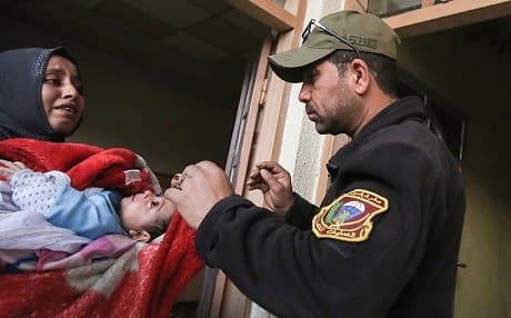 A member of the Iraqi special operations forces assists a mother and child in west Mosul. Photo: AFP