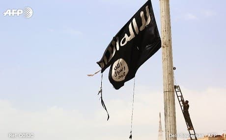 An SDF fighter takes down an ISIS flag in Tabqa. Photo: Delil Souleiman/AFP