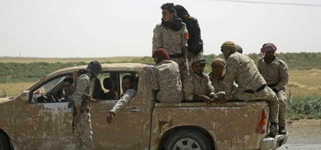 Members of the US-backed Syrian Democratic Forces (SDF) sit in the back of pick-up truck in the village of Hazima on the northern outskirts of ISIS's de facto capital of Raqqa on June 6, 2017. Photo: Delil Souleiman | AFP
