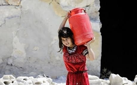 A Syrian girl carries a large jug of water on her back while on her way home, in the Kallaseh district of the northern city of Aleppo on July 5.  Photo: Joseph Eid |  AFP 
