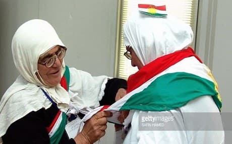 A Kurdish woman helps tie on a flag of Kurdistan fir a fellow pilgrim, prior to getting onto a flight from Erbil bound to Saudia Arabia, to take part in  the annual Hajj pilgrimage. File photo: getty images/Safin Hamed