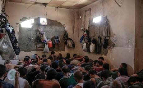 Suspected ISIS members sit inside a small room in a prison south of Mosul on Tuesday. Photo: Bram Janssen | AP